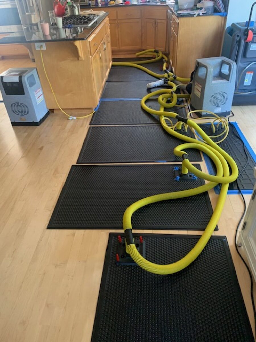 Drying mats and hoses arranged on flooring during mitigation